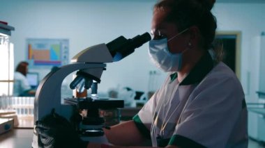 Bilim adamı araştırmacı virüs örneklerini mikroskop altında inceliyor. Kadın Araştırma Uzmanı Mikroskop Altında Biyolojik Örneklere Bakıyor