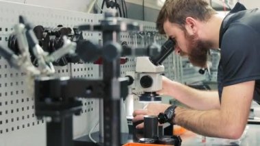 Diagnostik dizel enjektörler mikroskop altında. Usta, kusurları tespit etmek için başlığı mikroskop altında inceliyor.