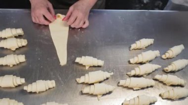 Fırıncı hamurdan kruvasan yapar. Hamurdan yapılmış şekerlemeler. Kruvasan üretimi için hamur bükülüyor..