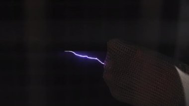 Tesla bobini elektrik boşalması. Elektrikli kavisler metal eldivenlere dokunur..