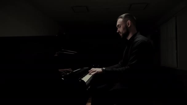 音楽家が暗いホールでピアノを演奏する プロのピアニストがピアノを弾く — ストック動画