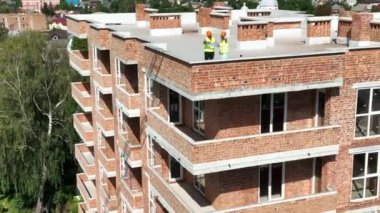 Bir tuğla evin inşaatı tamamlandı. Binanın çatısında inşaat mühendisleri var..