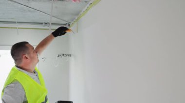 Odada tamirat ve duvarları boyamak. Ressam duvarları silindirle beyaza boyar..