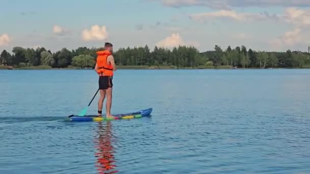 一个穿着救生衣的男人在湖心区的木板上湖上的运动生活方式 — 图库视频影像