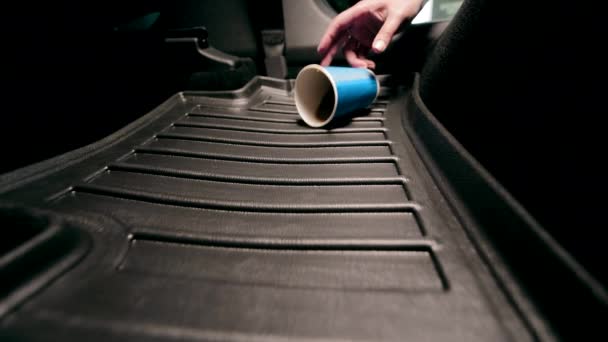 把咖啡洒在车上的地毯上 小木屋里汽车的污染 一杯装有咖啡的蓝色一次性杯子落在车底垫子上 — 图库视频影像
