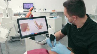 Diş hekimi CEREC tarayıcısını kullanarak hastaların dişlerini tarıyor. Modern dişçilik. Diş hekimi hastaların dişlerini taramak için 3 boyutlu diş içi tarayıcı kullanır..