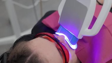 Dişlerinin beyazlatıldığı sırada bir kadının yüzüne yakından bakın. Modern bir diş kliniğinde dişlerin lazerle canlandırılması.