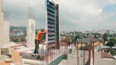 İnşaatçı inşaat alanında çalışıyor. Metal yapıların monolit ile doldurulması. Miğfersiz ve yansıtıcı yeleği olmayan yapıcı