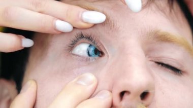 Temas Lenslerini Mavi Göze Uygulayacak Adam. Ophthalmology Outdoor sırasında beyaz manikürlü sakallı erkeğe yardım eden kadın ellerini kapatın. Görüş Konsepti.