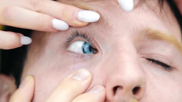 男人在蓝眼睛上涂隐形眼镜 在眼科护理室外时 用白色指甲紧闭女性的手 帮助有胡子的男性 视觉概念 — 图库视频影像