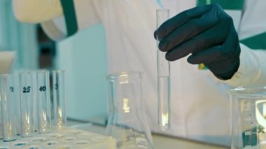 Test tüpüne şeker kutusuyla bir damla kimyasal reaktör eklemenin yakın çekimi. Laboratuvarda test tüpleri ve ilaçlarla çalış..