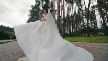 Bir gelin düğün gününde parkta koşuyor. Düğününe geç kalan bir gelin. Hızlı hareketten yükselen büyüleyici bir gelinlik.