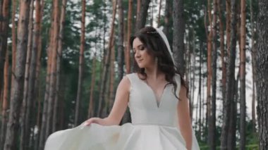 Güzel bir gelin ormanın yakınında dans eder, beyaz bir elbiseyle kendi etrafında döner..