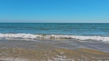 Güneşli bir günde sakin bir hava. Küçük dalgalar kıyıya ulaşır. İnsanlar olmadan yüzme mevsiminin sonu ya da başlangıcı