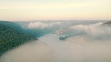 Nehre yayılan sabah sisinin en üst görüntüsü. Bulutların arasından nehir kanyonunun güzel bir manzarası. Resimli bir kanyonda bir dinlenme merkezi. Hava görünümü.