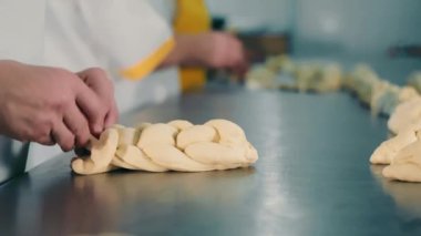 Örgülü ekmek üretimi, örgülü ekmek. Kapatın. Fırıncı, ekmek yapmak için hamur örgüsü örer.