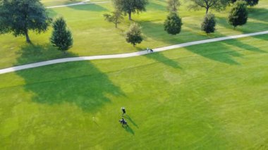 Golf sahasında bir adam topa vuruyor. Golf sahası yukarıdan, oyuncu sahada ve işçi. Hava görünümü.