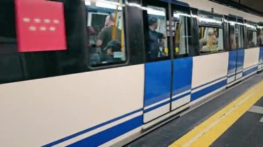 Madrid, İspanya - 15 Eylül 2023: Hızlı bir trenle tünelden ayrılan ve yavaşlayan metro istasyonu, yolcularla birlikte durağa yaklaşıyor. Kalabalık tren vagonları, kalabalık saatler.