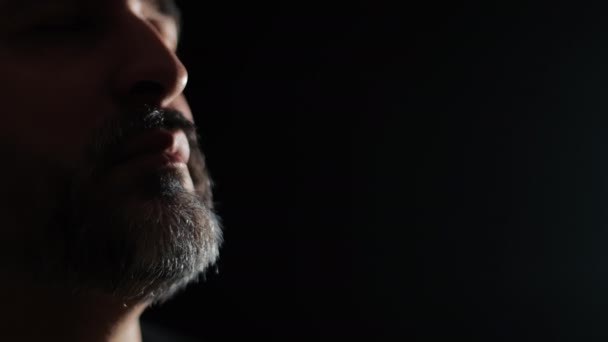 一个有着灰白胡子的中年男子的脸 背景是漆黑的 — 图库视频影像