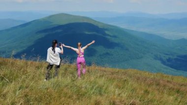 Dağın tepesinde telefonla fotoğraf çeken iki kadın turist. Arkadaşlarıyla dağlarda dinlenip yürüyüş yapıyor. Turizm ve aktif yaşam tarzı