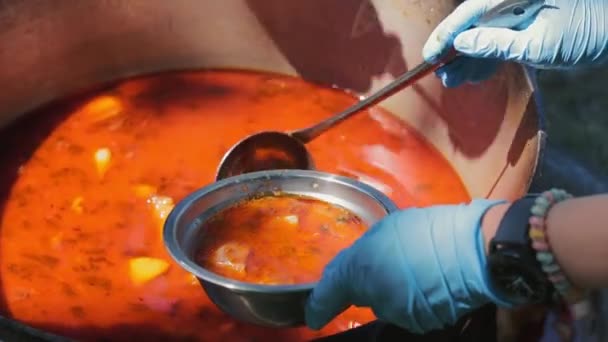 厨师把红肉汤装进金属碗里 室外大锅大锅或罗宋汤的特写镜头 女性手拿着厨房大勺 野营季节 — 图库视频影像