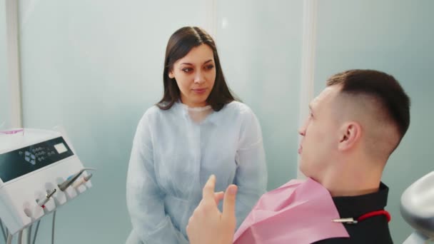 歯科医 患者とのプロシージャを議論 歯科治療を患者に説明保護マスクで歯科医 — ストック動画