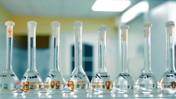科学实验室的容量测量瓶 科学实验室一排排装有清澈液体的容量测量瓶 — 图库视频影像
