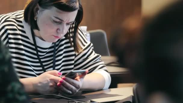 スマートフォンを活用したビジネスマン 職場でスマートフォンを使用したストライプセーターの集中女性 — ストック動画