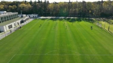 Futbol antrenmanının genel görünümü, top ve kale direkleri ile sahada antrenman yapan futbolcuları yakalamak.