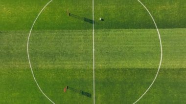 Eğitim ekipmanlarıyla bir futbol sahasının havadan görüntüsü. Kale direkli bir futbol sahası ve ortasında tek bir top..