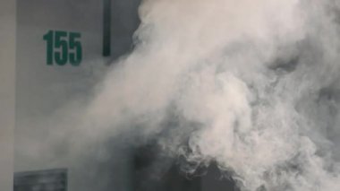 Yeraltı otoparkında duman. Duvardaki numaralandırılmış park yerlerini bir duman bulutu kaplıyor..
