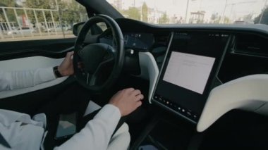 Modern Elektrikli Araç sürücüsü, beyaz tişörtlü adam, yüksek teknolojili elektrikli arabanın içinde dokunmatik ekran paneli kullanıyor..