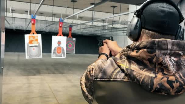 男子在室内练习射击 身着迷彩服的人将手枪对准射击场内的目标 专注于精准和安全 — 图库视频影像