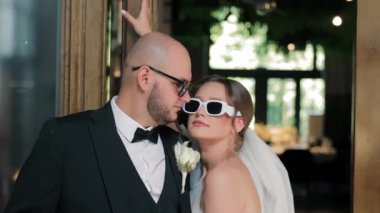 Güneş gözlüğü takan şık gelin ve damat, güneş gözlüğü takan şık bir gelin ve damat kapalı alanda neşeli bir anı paylaşıyor.