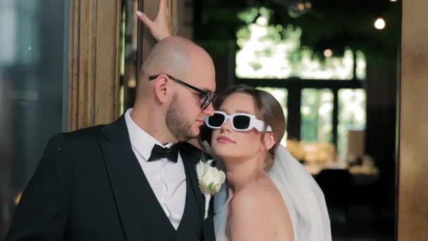 シックな花嫁とグロム サングラスを着用 スタイリッシュな花嫁とサングラスを着用して 屋内で遊び心のある瞬間を共有 — ストック動画