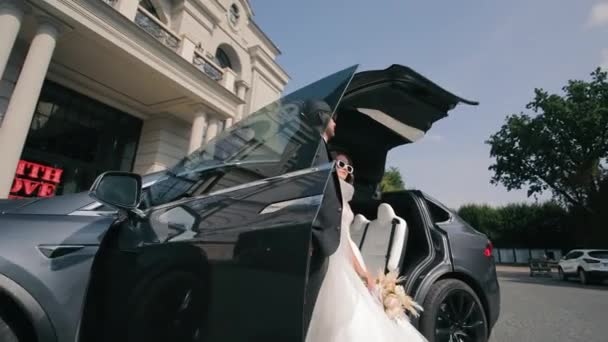 ラグジュアリー車 洗練された花嫁 サングラスのグルーミングは 結婚式の日に高級車でポーズします — ストック動画
