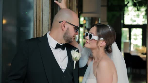 サングラスで花嫁とグルーミングのビュー 結婚式の日に花嫁と柔らかい瞬間を共有するサングラスの遊び心のある花嫁 — ストック動画