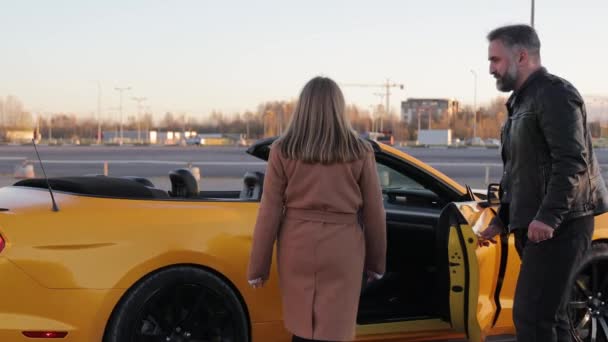 Ζευγάρι Κίτρινο Μετατρέψιμο Αυτοκίνητο Στο Sunset Ένας Άνδρας Βοηθά Μια — Αρχείο Βίντεο