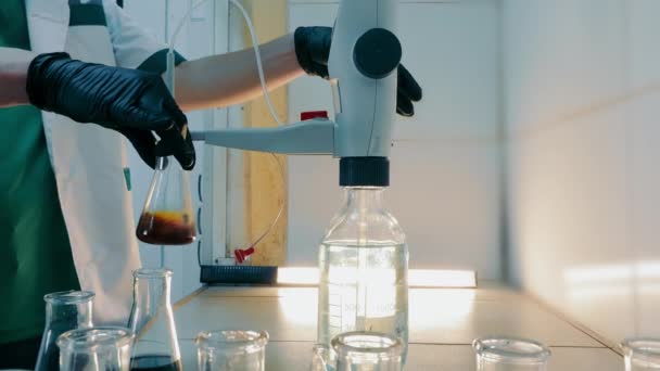 实验室技师调整瓶 科学家调整瓶与黑暗液体在实验室设备下 — 图库视频影像