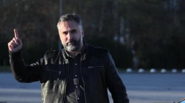 Motion Musician Cueing Next Beat 'te ritim, sakallı, olgun bir adam ritmi takip ediyor, açık havada arka planda bulanıklık var.