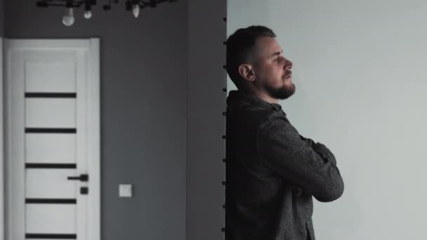 一个孤独的男人站在房间里 一个沉思的男人 双臂交叉地站在一个简约的房间里 陷入沉思 — 图库视频影像