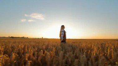 Sunset 'te buğday tarlasında bir kadın geleneksel kıyafetli bir kadın günbatımında geniş buğday tarlasında tek başına duruyor.