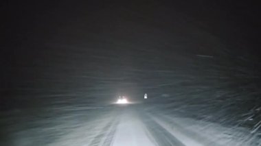 Gece araba farlarında Karlı Yol, gece kar fırtınası sırasında arabanın farları karlı bir yolu aydınlatıyor.