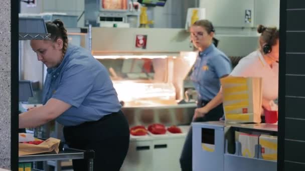 デュッセルドルフ ドイツ 2024マクドナルドファストフードレストランスタッフ サービス中に ファーストフードレストランのキッチンでフードサービスで忙しい労働者 — ストック動画
