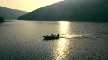 Hava manzaralı Tranquil Nehri Günbatımında bir tekne batan güneşin altın ışığıyla parıldayan bir nehirde süzülüyor.