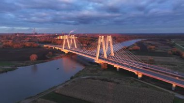 Polonya 'nın Krakow şehrinde alacakaranlıkta köprüde hava trafiği hareket ediyor. Modern kablo destekli köprülerin yakın çekimi Krakow 'daki alacakaranlık gökyüzünün arka planına karşı mimariyi karmaşıklaştırır.