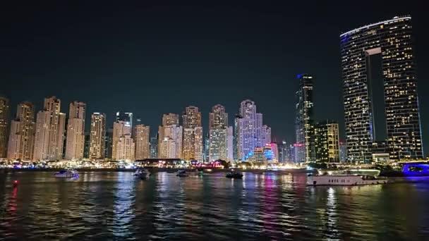 Uae ドバイ アラブ首長国連邦 4月2024 タイムトラフィックJbrビーチドバイマリーナスカイラインナイト 夜にクルーズボートでドバイマリーナのスカイラインと水路を照らす — ストック動画
