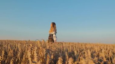 Gün batımında altın buğday tarlasında tefekkür eden bir kadın günbatımında geniş bir buğday tarlasında duruyor, dinginliği somutlaştırıyor..