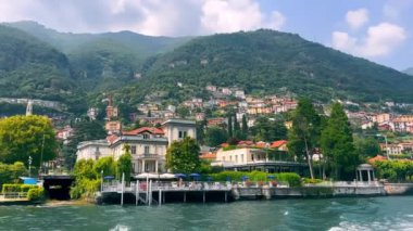Como Gölü 'ndeki renkli rıhtım kasabası, Como Gölü' nün canlı ve resimli deniz manzarası zarif binalar ve kayan tepelerin arkasındaki yemyeşil ağaçlar.