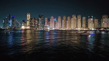 BAE, Dubai - Birleşik Arap Emirlikleri 01 Nisan 2024 Dubai Marina Nightscape with Yachts, Dubais şehir ışıkları yat limanında demirlemiş lüks yatlarla gece sularını yansıtıyor